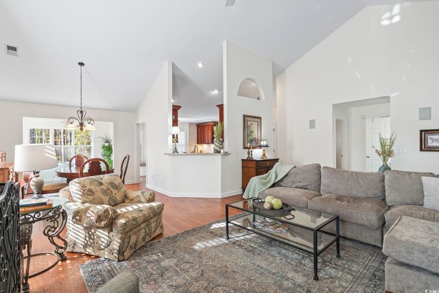 living room with high vaulted ceiling, wood-type flooring, and a chandelier