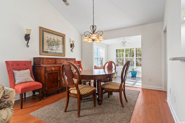 dining room featuring vaulted ceiling, ceiling fan with notable chandelier, and light hardwood / wood-style flooring