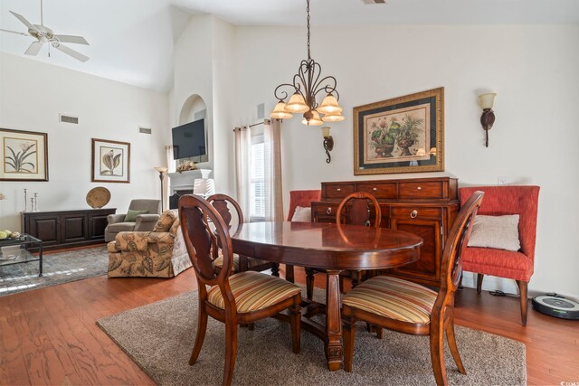 dining room featuring hardwood / wood-style flooring, high vaulted ceiling, and ceiling fan with notable chandelier