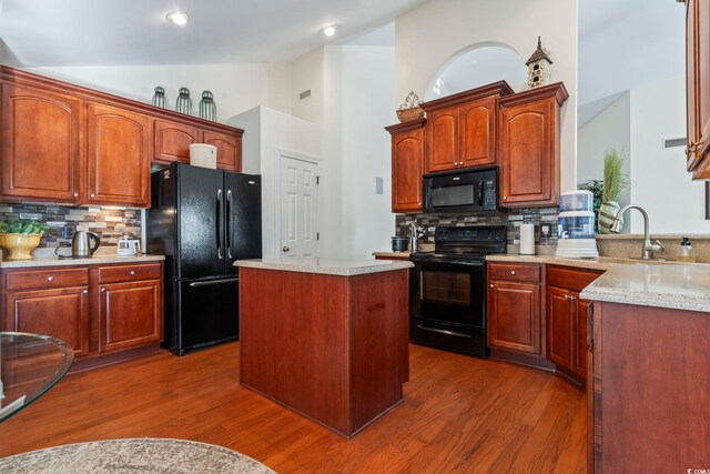 kitchen with black appliances, a kitchen island, dark hardwood / wood-style flooring, decorative backsplash, and sink