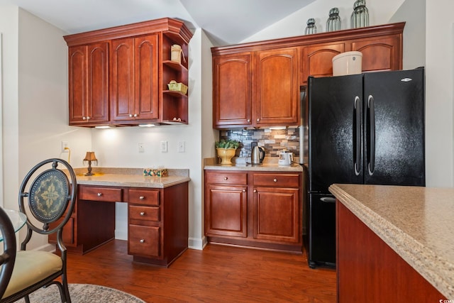 kitchen with backsplash, dark hardwood / wood-style floors, black fridge, and vaulted ceiling