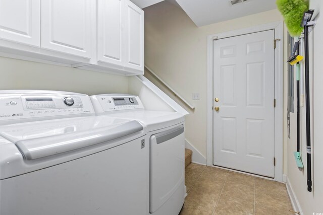 clothes washing area with cabinets, separate washer and dryer, and light tile patterned floors