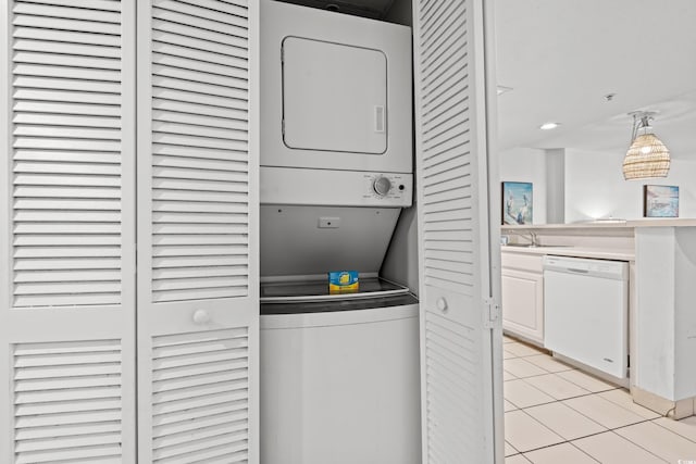 washroom with light tile patterned floors, sink, and stacked washer and dryer