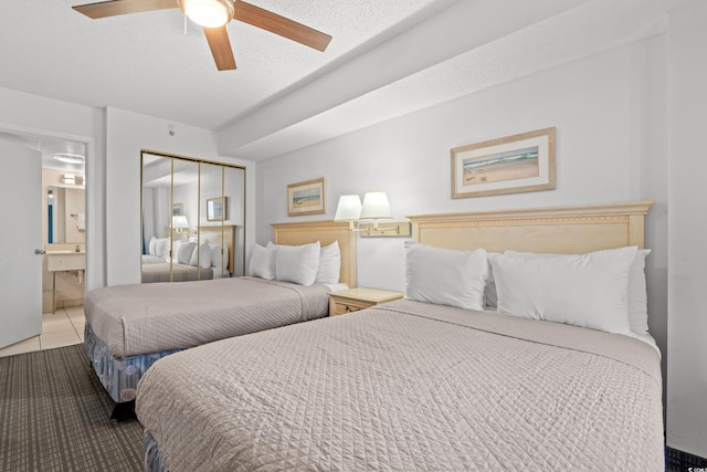 tiled bedroom with ensuite bath, a textured ceiling, ceiling fan, and a closet