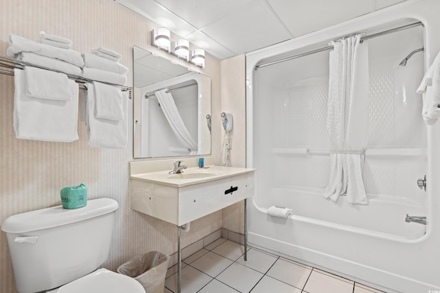 full bathroom with sink, a drop ceiling, toilet, tile patterned floors, and shower / bath combo with shower curtain