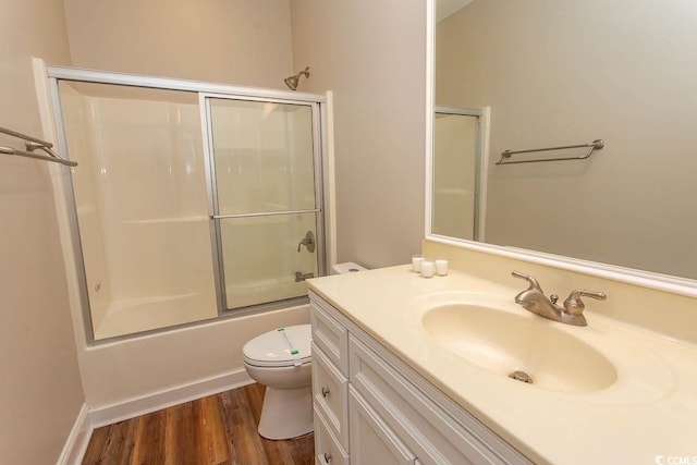 full bathroom with combined bath / shower with glass door, toilet, vanity, and hardwood / wood-style flooring