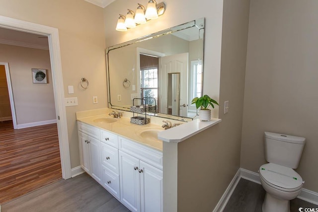 bathroom with toilet, vanity, ornamental molding, and hardwood / wood-style flooring