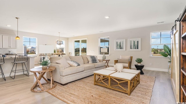 living room with light hardwood / wood-style floors and a notable chandelier