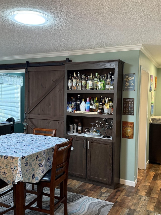 bar featuring a textured ceiling, dark hardwood / wood-style floors, a barn door, crown molding, and dark brown cabinets