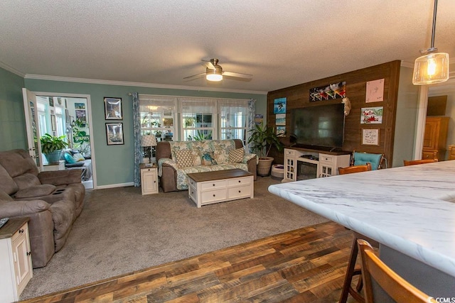 living room with a textured ceiling, ceiling fan, crown molding, and dark carpet