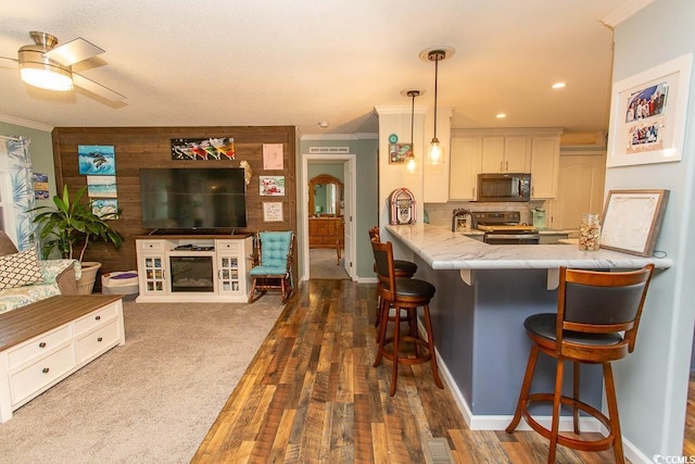 kitchen featuring decorative light fixtures, white cabinetry, a kitchen bar, kitchen peninsula, and stainless steel range with electric stovetop