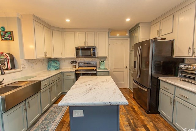 kitchen featuring stainless steel appliances, decorative backsplash, gray cabinets, a kitchen island, and dark hardwood / wood-style flooring