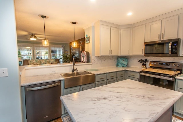 kitchen featuring kitchen peninsula, hanging light fixtures, stainless steel appliances, gray cabinetry, and sink