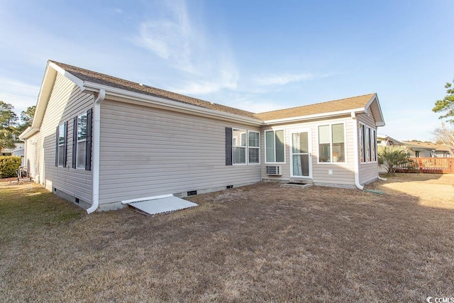 back of property with a wall unit AC and a lawn