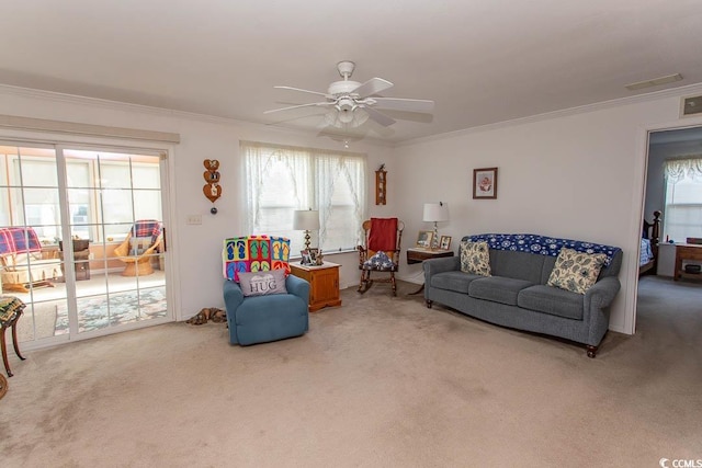 living room with ceiling fan, ornamental molding, and carpet