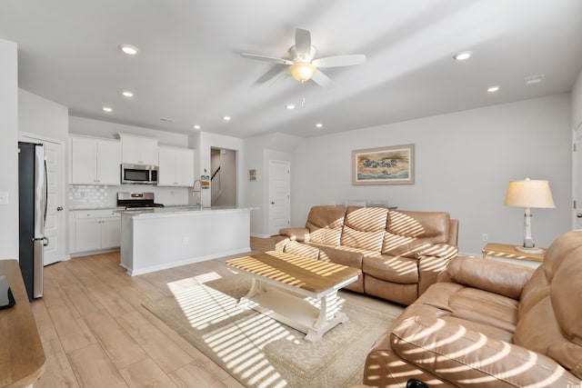 living room with ceiling fan and light hardwood / wood-style flooring