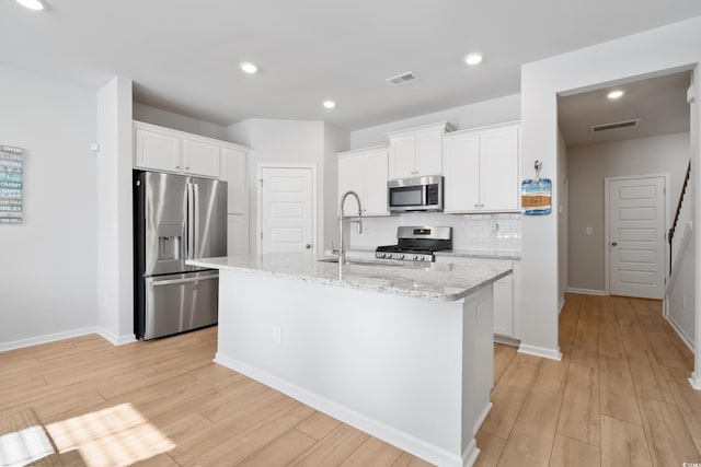 kitchen with sink, white cabinets, stainless steel appliances, and an island with sink