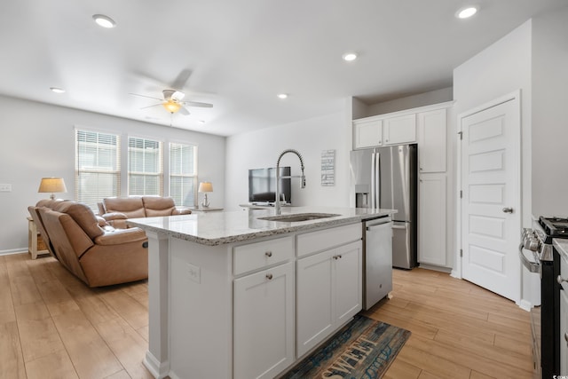 kitchen with ceiling fan, white cabinetry, stainless steel appliances, and an island with sink