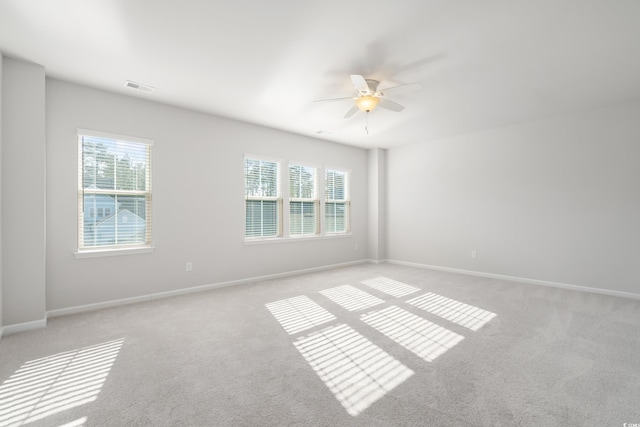 spare room featuring ceiling fan, a wealth of natural light, and light colored carpet