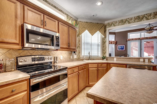 kitchen featuring stainless steel appliances, light tile patterned floors, decorative backsplash, crown molding, and sink