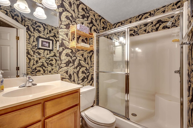 bathroom featuring toilet, vanity, a textured ceiling, and walk in shower