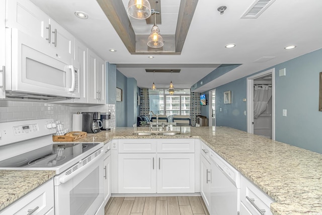 kitchen with white appliances, light wood-style flooring, a sink, white cabinets, and tasteful backsplash