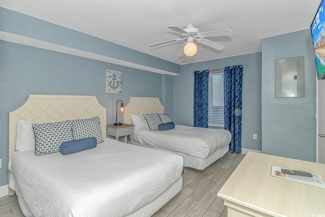 bedroom with electric panel, a ceiling fan, baseboards, and wood finish floors