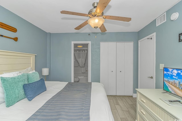 bedroom featuring wood finish floors, visible vents, a ceiling fan, a closet, and connected bathroom