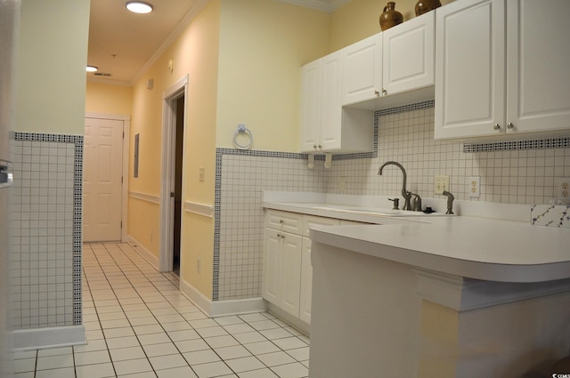 kitchen with white cabinetry, sink, ornamental molding, light tile patterned floors, and kitchen peninsula