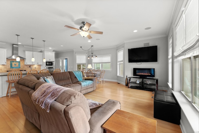 living room with ceiling fan, crown molding, and light hardwood / wood-style floors