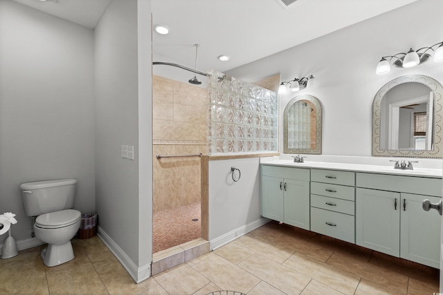 bathroom featuring a tile shower, toilet, vanity, and tile patterned flooring