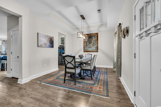 dining area featuring dark hardwood / wood-style floors and a tray ceiling