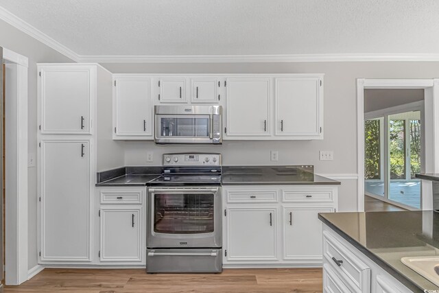 kitchen with appliances with stainless steel finishes, white cabinets, and light wood-type flooring