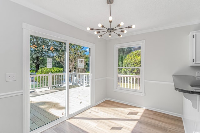 entryway featuring a notable chandelier, crown molding, light hardwood / wood-style floors, and a textured ceiling