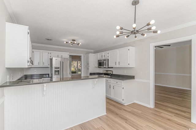 kitchen with ornamental molding, appliances with stainless steel finishes, kitchen peninsula, and white cabinets