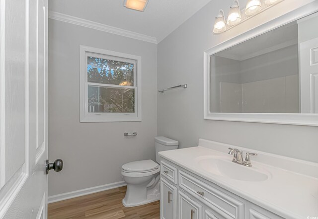 bathroom featuring hardwood / wood-style flooring, vanity, ornamental molding, and toilet