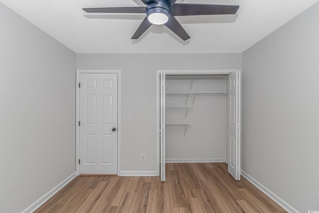 unfurnished bedroom with a textured ceiling, a closet, ceiling fan, and light wood-type flooring