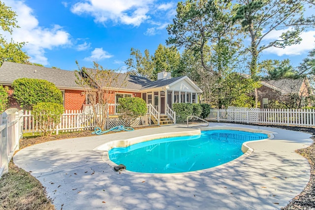 view of swimming pool featuring a patio and a sunroom