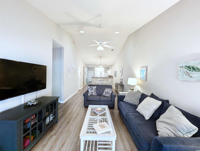 living room with ceiling fan, vaulted ceiling, and light hardwood / wood-style flooring