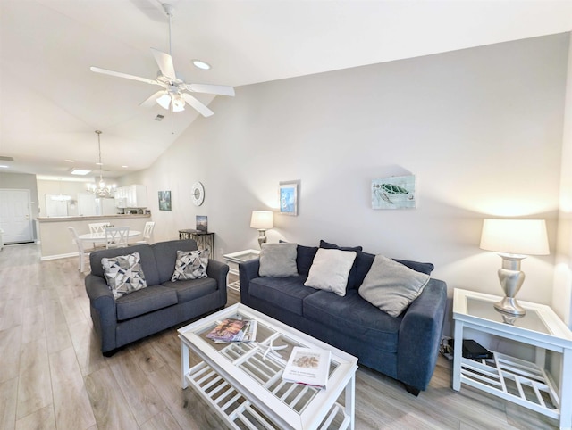 living room featuring light hardwood / wood-style flooring, vaulted ceiling, and ceiling fan with notable chandelier