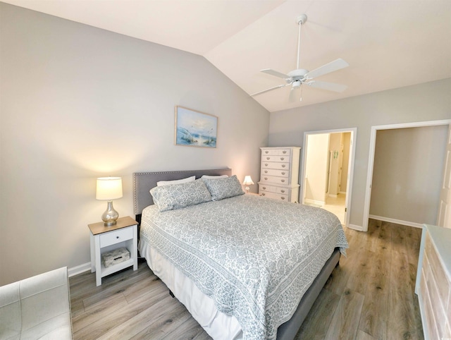 bedroom featuring ceiling fan, connected bathroom, lofted ceiling, and hardwood / wood-style flooring