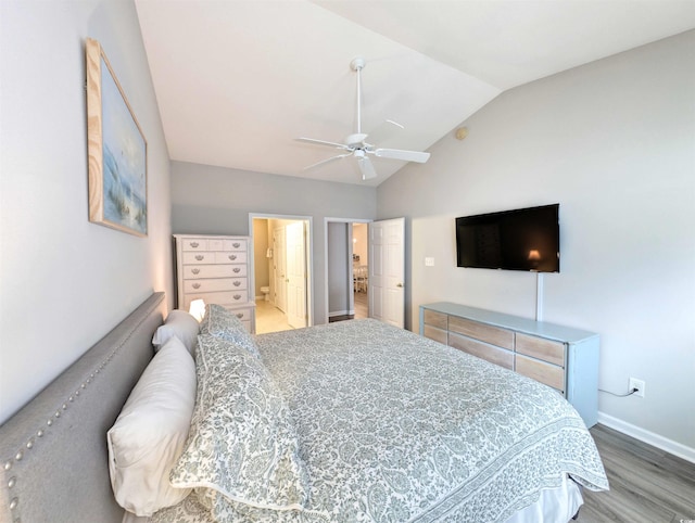 bedroom with vaulted ceiling, ensuite bath, ceiling fan, and hardwood / wood-style flooring