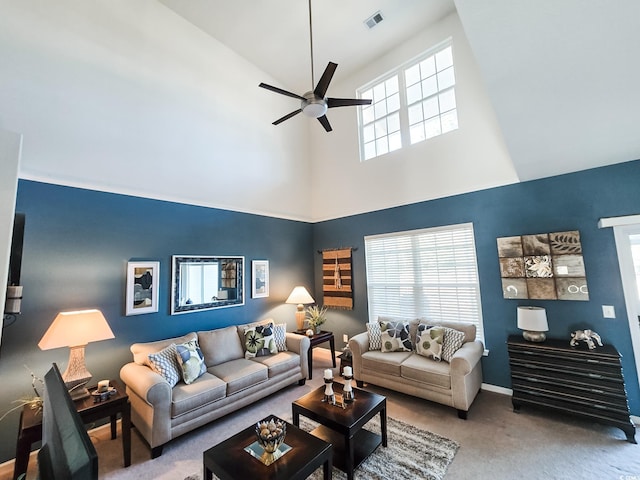 carpeted living room featuring ceiling fan and a towering ceiling