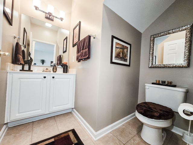 bathroom featuring toilet, vanity, tile patterned floors, and vaulted ceiling