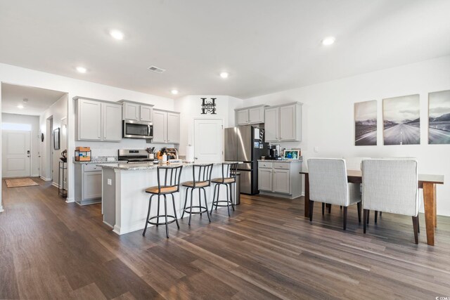 kitchen with a kitchen island with sink, appliances with stainless steel finishes, and gray cabinetry