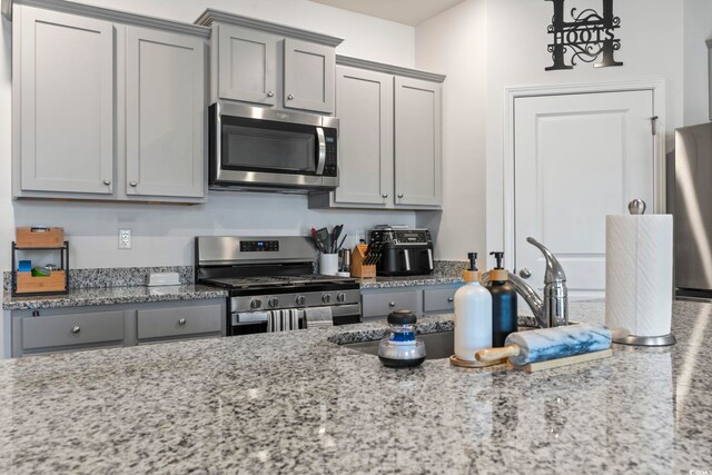 kitchen featuring light stone countertops, gray cabinets, and stainless steel appliances