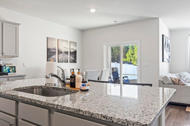 kitchen with dark hardwood / wood-style flooring, sink, light stone counters, and gray cabinets