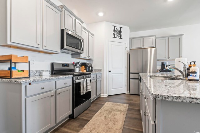 kitchen featuring dark wood-type flooring, stainless steel appliances, gray cabinetry, and sink