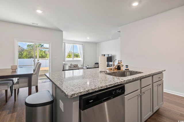 kitchen featuring dark wood-type flooring, sink, stainless steel dishwasher, and an island with sink