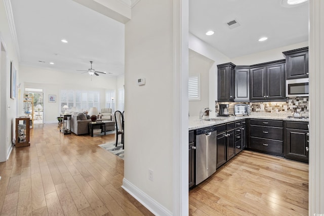 kitchen featuring stainless steel appliances, ornamental molding, decorative backsplash, and light hardwood / wood-style flooring